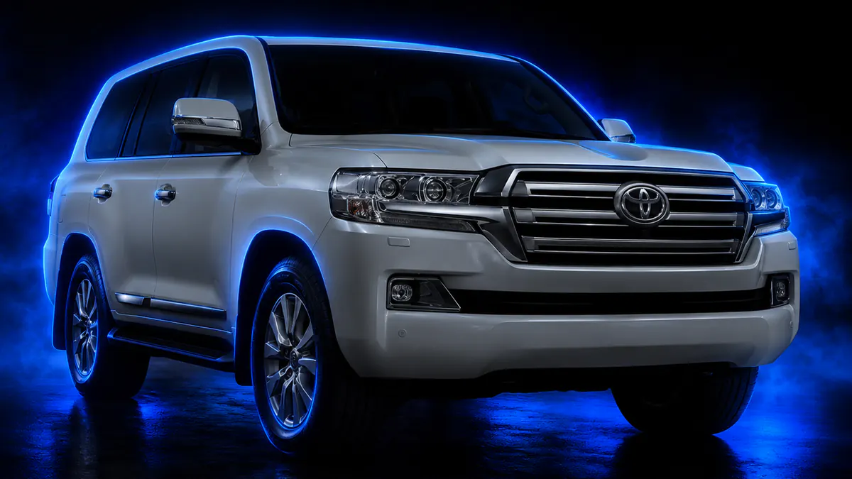 Toyota Land Cruiser 200 Series in pearl white, blue rim light tracing the roofline in a dark studio, three-quarter front view